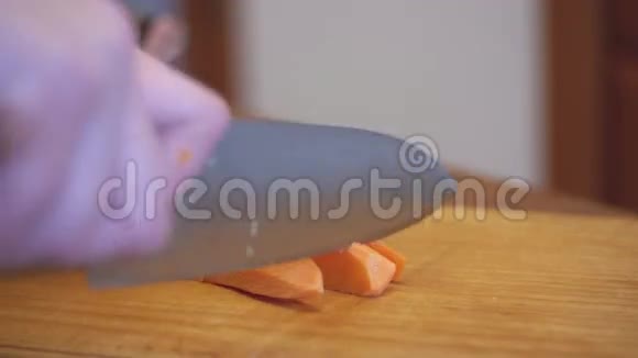 在家庭厨房的木制厨房板上用刀切割胡萝卜的女人手视频的预览图