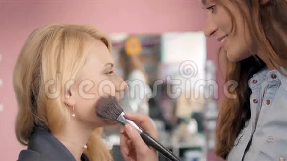 化妆师用年轻的女人做专业的化妆用设计师的手刷视频的预览图