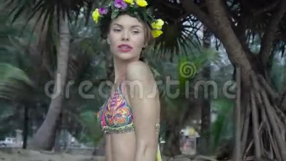 在美丽的夏日棕榈树间穿着五颜六色的泳装和花环的女人视频的预览图