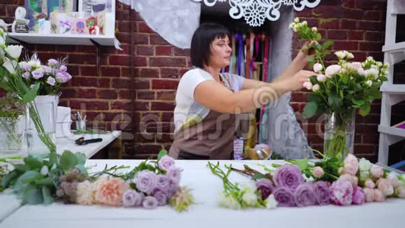 专业花艺师在花艺设计工作室挑选玫瑰花枝进行花束布置视频的预览图