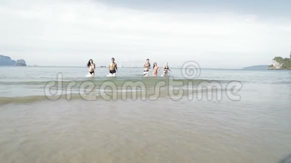 人们从沙滩上的水中奔跑青年男女游客视频的预览图
