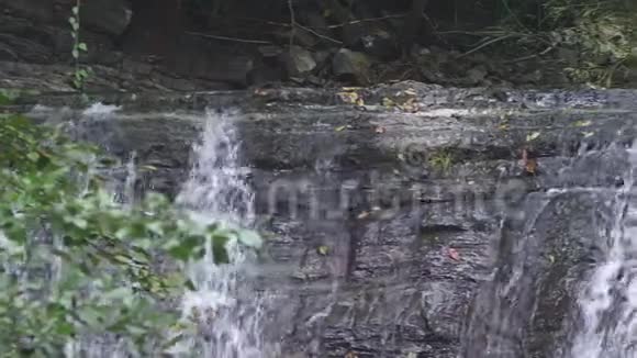 特写镜头落石山上的瀑布水流迅速下坠生成白色起泡泡沫石头瀑布视频的预览图