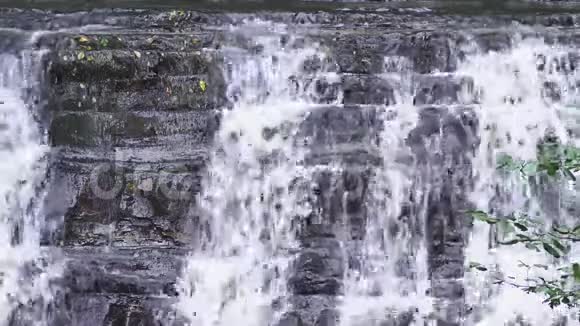特写镜头落石山上的瀑布水流迅速下坠生成白色起泡泡沫石头瀑布视频的预览图