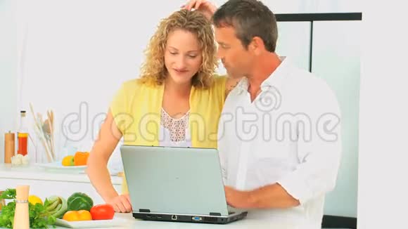 偶然的一对夫妇看着笔记本电脑上的食谱视频的预览图