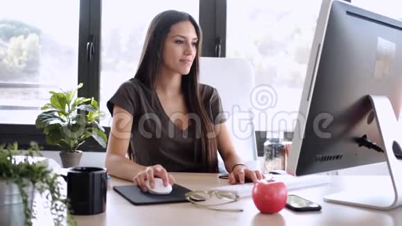 微笑的年轻女商人在办公室里用电脑工作视频的预览图
