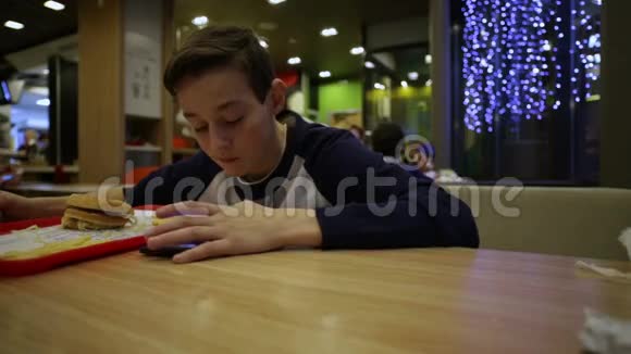青少年吃汉堡玩智能手机视频的预览图