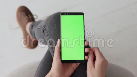 Chroma键模型与绿色屏幕上的年轻女子在家里的手机视频的预览图