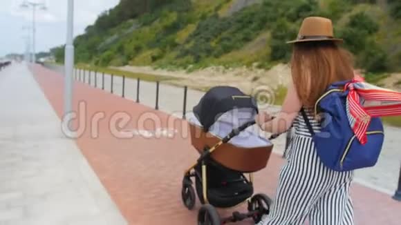 现代年轻的母亲带着婴儿车在长廊散步家庭母性和人的概念有婴儿的幸福母亲视频的预览图