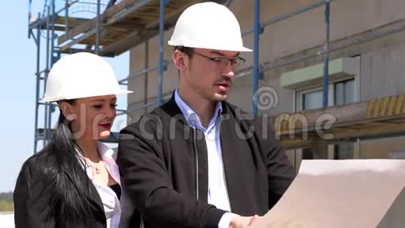 两名戴白盔的建筑师在工地上讨论一项计划视频的预览图
