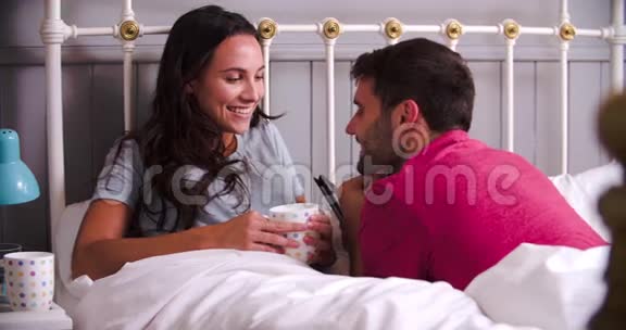 年轻夫妇在床上热饮放松视频的预览图