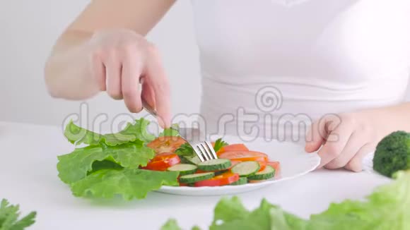 坐在餐桌前吃新鲜蔬菜沙拉的女士特写视频的预览图