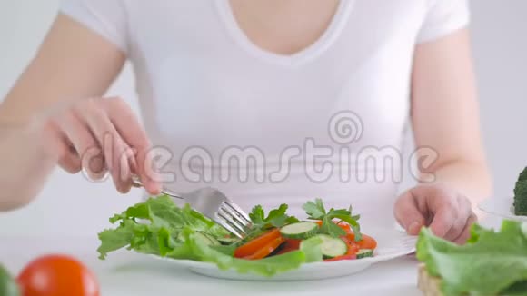 坐在餐桌前吃新鲜蔬菜沙拉的女士特写视频的预览图