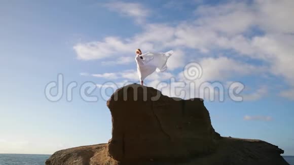 自由概念穿着白色衣服戴着围巾的女人站在岩石上跳舞飞行移动视频的预览图