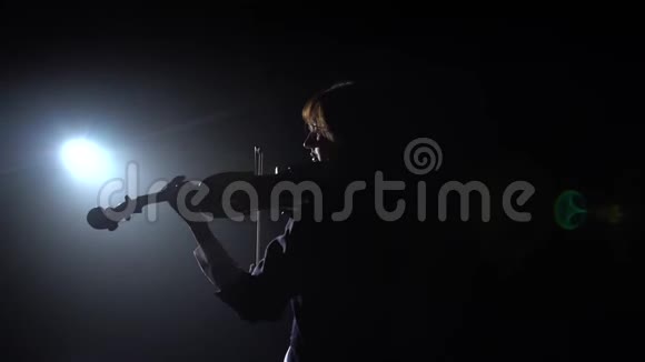 女孩站在后面在黑暗的房间里演奏小提琴黑烟背景背面视频的预览图