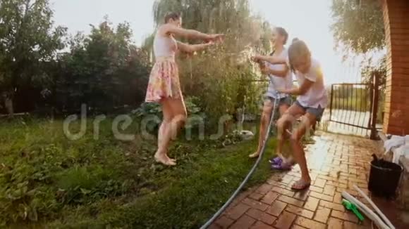 快乐儿童从花园水管中泼水的慢动作视频视频的预览图