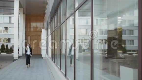 美丽的商务女性在商务中心外散步和打电话视频的预览图