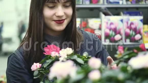 年轻漂亮的女人在花店里选择花视频的预览图