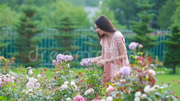 美丽的玫瑰花丛中花园里的小女孩玫瑰的气味视频的预览图