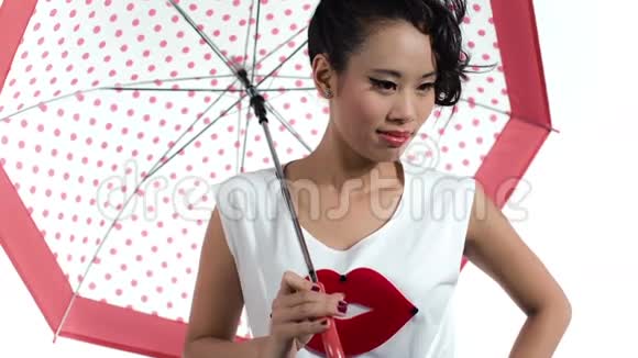 亚洲女人带着一把带有圆点图案的伞在工作室里摆姿势视频的预览图