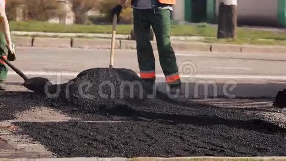 一名工人正在农村公路上用冷沥青平整变形视频的预览图
