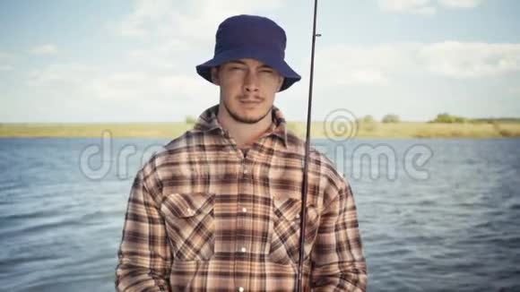 年轻的渔夫积极在湖边钓鱼视频的预览图