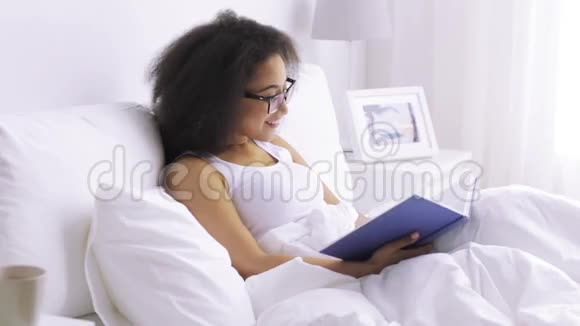 非洲妇女在家卧室的床上看书视频的预览图