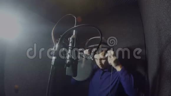 戴着耳机的男歌手在录音室演唱歌曲视频的预览图