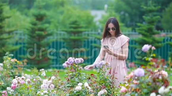 美丽的玫瑰花丛中花园里的小女孩玫瑰的气味视频的预览图