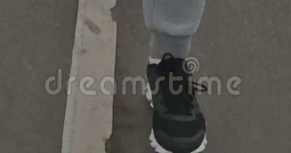 一个穿运动鞋的人在城外的沥青上跑步视频的预览图