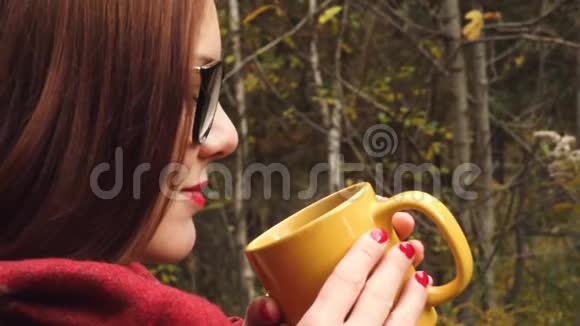 年轻女子从杯子里喝热茶以保暖视频的预览图