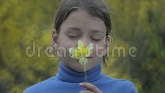 春天一个男孩和一朵黄色水仙花的肖像神秘的男孩闻着水仙花视频的预览图