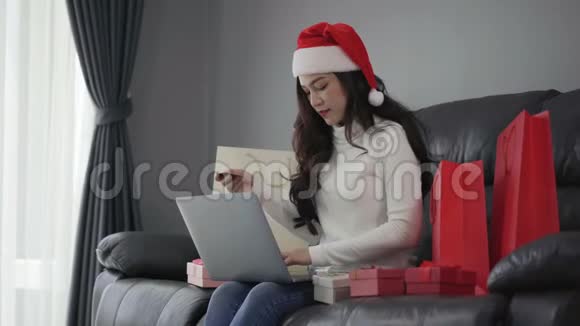 女士在网上购物圣诞礼物和笔记本电脑客厅视频的预览图