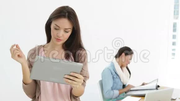 创意女商人使用平板电脑的同事在她身后视频的预览图