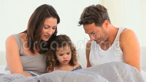 可爱的父母带着女儿躺在床上视频的预览图