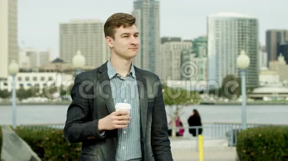 年轻的帅哥正在人行道上喝茶视频的预览图