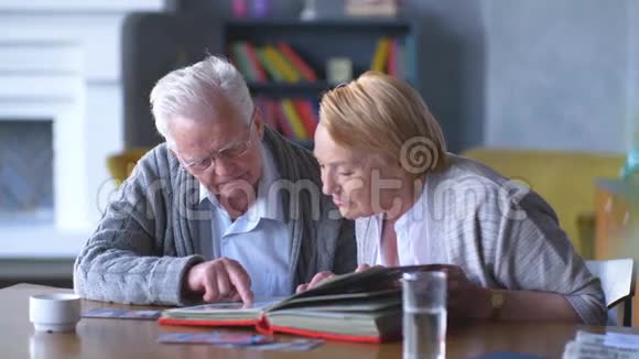 一对幸福的老人看着旧相册微笑着视频的预览图
