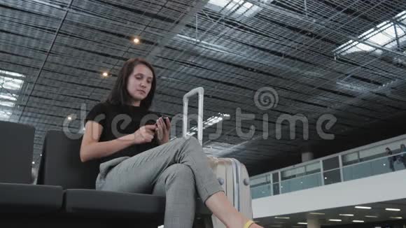 年轻漂亮的女商人在机场使用智能手机等待排队登记旅行概念视频的预览图