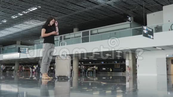 年轻漂亮的女商人在机场使用智能手机等待排队登记旅行概念视频的预览图