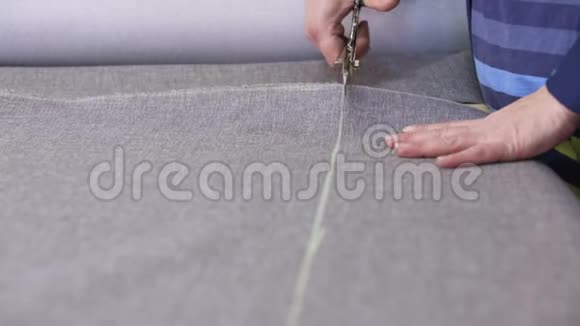 家具厂的一位年长妇女正在为沙发剪一种灰色材料视频的预览图