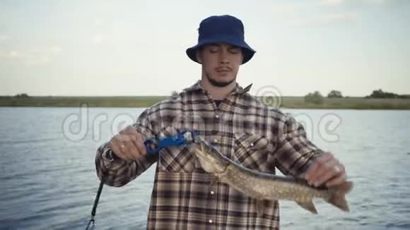 年轻的渔夫积极在湖边钓鱼视频的预览图