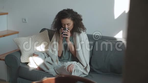 微笑的女人在家喝咖啡或茶的肖像视频的预览图