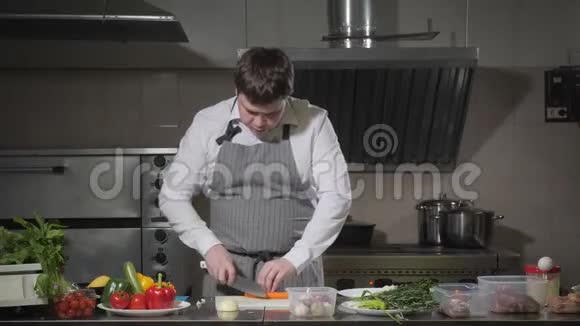 年轻的厨师在白色的切割板特写上切胡萝卜在餐厅厨房做饭视频的预览图