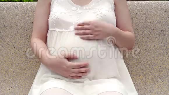 年轻的孕妇抚摸着肚子视频的预览图