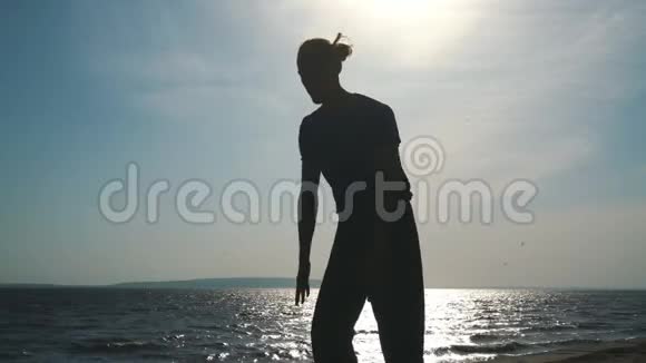在日落海滩做瑜伽的年轻人剪影视频的预览图