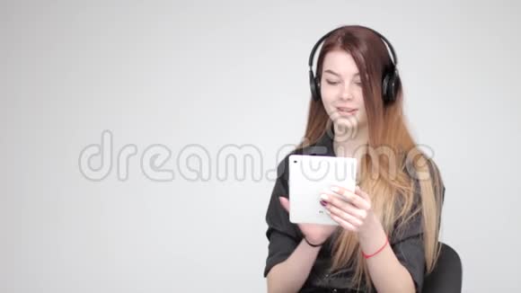 年轻快乐漂亮的女孩摆着白色平板电脑在智能手机上拍照视频的预览图