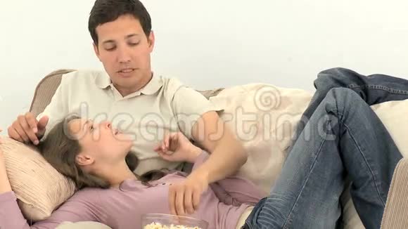 可爱的一对夫妇坐在沙发上看电视视频的预览图