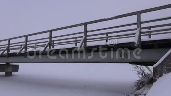 冬季和晨雾雪湖上的老木桥视频的预览图