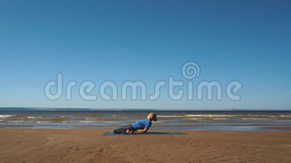 强壮的男人在海滩上练习困难的瑜伽姿势视频的预览图