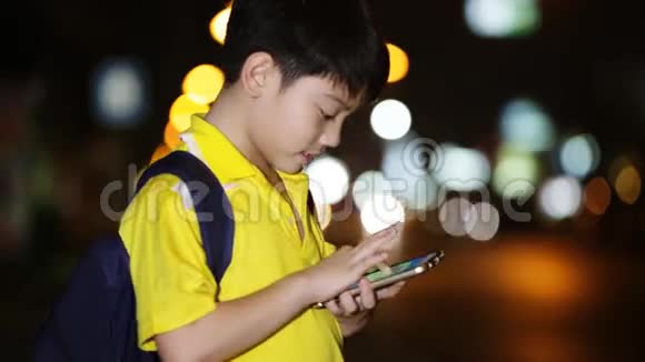 亚洲小孩在夜间灯光背景下玩智能手机视频的预览图