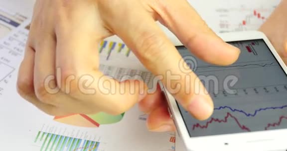 商人在智能手机上浏览金融新闻手指触摸金融饼图视频的预览图